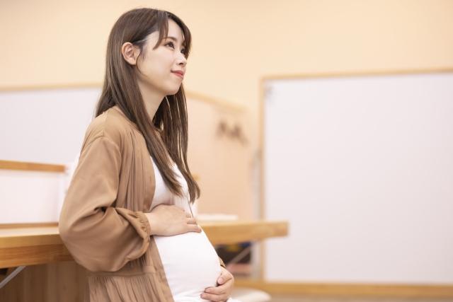 おなかに手を当てて前を見つめる妊婦さん