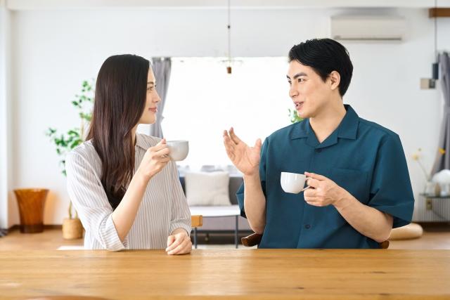 テーブルでコーヒーを飲みながら話し合う夫婦