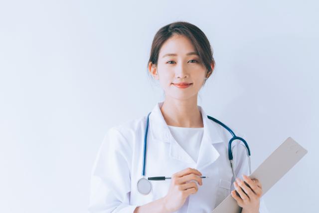 カルテを持ってほほえむ女性医師