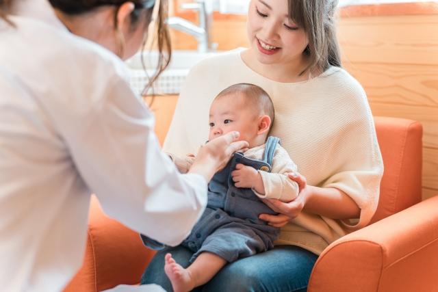 母親に抱かれた赤ちゃんを診察する医師